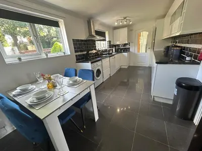 a kitchen with a table and blue chairs in it at Luxurious 3 Bedroom Contractor House Stevenage by Randz Property Group - Short Lets l Sleeps 6 l Free Parking & Wifi in Stevenage