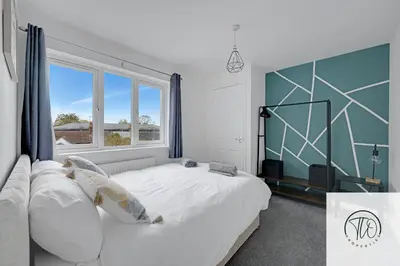 a bedroom with a large bed and a large window at Jardine House in Colchester