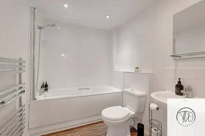 a white bathroom with a tub and a toilet at Jardine House in Colchester
