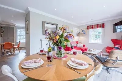 a living room with a wooden table with a vase of flowers at The Poppies, a stylish Aldeburgh holiday home in Aldeburgh