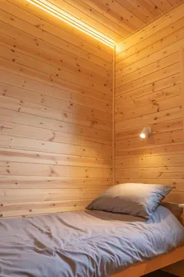 a bed in a room with a wooden wall at The Bell Inn in Wendens Ambo