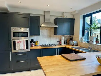 a kitchen with blue cabinets and a wooden counter top at Beautiful Victorian House in Central Chelmsford in Chelmsford