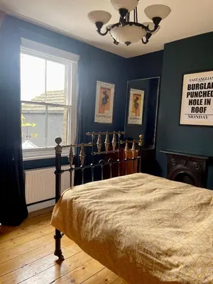 a bedroom with a bed with blue walls and a window at Beautiful Victorian House in Central Chelmsford in Chelmsford