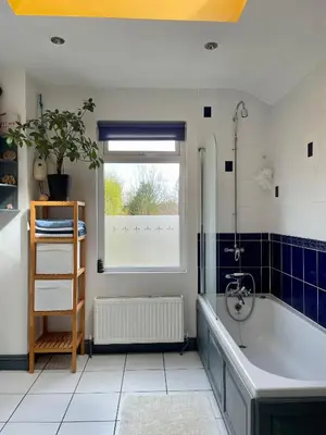 a bathroom with a bath tub and a window at Beautiful Victorian House in Central Chelmsford in Chelmsford