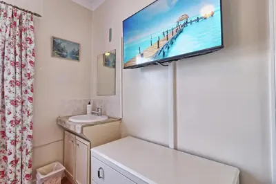 a bathroom with a sink and a tv on the wall at Walton Beach Holiday Lets in Walton-on-the-Naze
