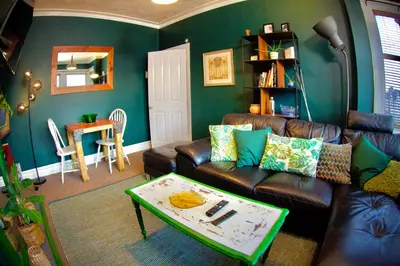 a living room with a leather couch and a table at Stylish and artistic flat in Southend on Sea - 2 Double Bedrooms, Free on-street parking in Southend-on-Sea