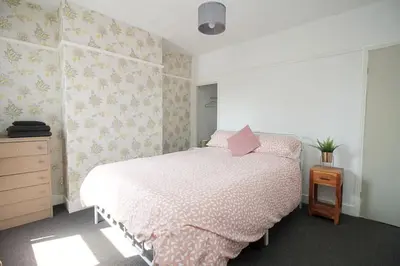 a bedroom with a bed with a pink comforter at Cottage in Walton on the Naze in Walton-on-the-Naze