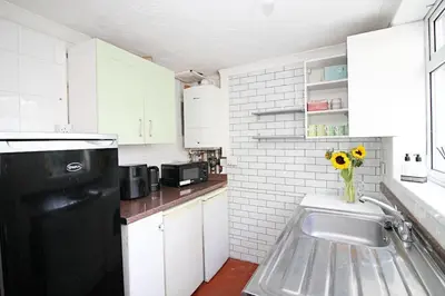 a kitchen with a black refrigerator and a vase of sunflowers at Cottage in Walton on the Naze in Walton-on-the-Naze