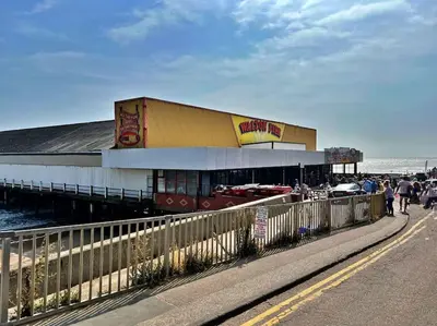 a building on a sidewalk next to a pier at Cottage in Walton on the Naze in Walton-on-the-Naze