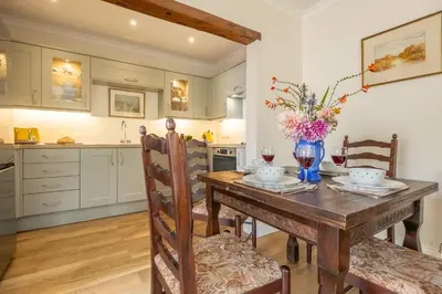 a kitchen with a wooden table with a vase of flowers on it at Rural bolthole in Constable country estate - The Woodshed in Higham