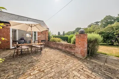 a patio with a table and an umbrella at Rural bolthole in Constable country estate - The Woodshed in Higham