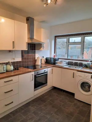a kitchen with white cabinets and a sink and a dishwasher at Homely Space in Havering, Essex in Havering atte Bower