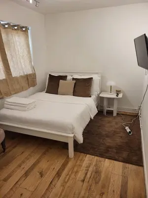 a bedroom with a white bed and a television at Homely Space in Havering, Essex in Havering atte Bower