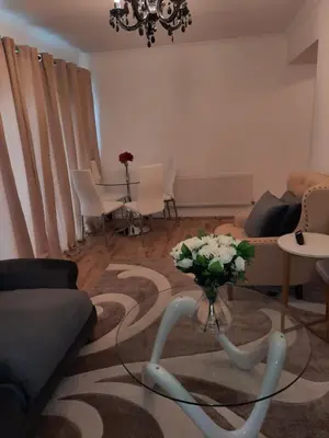 a living room with a couch and a table with flowers at Homely Space in Havering, Essex in Havering atte Bower