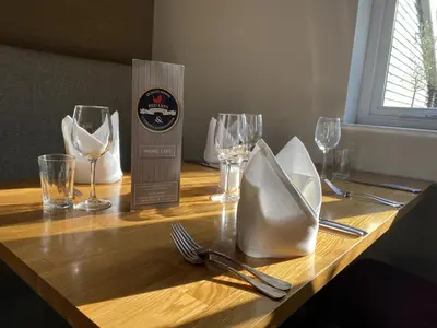 a wooden table with wine glasses and utensils on it at Red lion little barn in Ipswich
