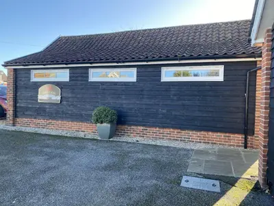 a black building with a potted plant in front of it at Red lion little barn in Ipswich