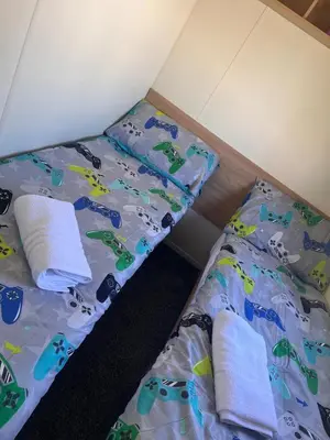 two beds in a small room with a bedspread with cars on it at 3 Bed Caravan Sleeps 8 - Parking Bbq Pool in Clacton-on-Sea
