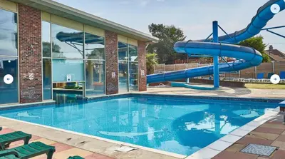 a swimming pool with a slide in front of a building at 3 Bed Caravan Sleeps 8 - Parking Bbq Pool in Clacton-on-Sea