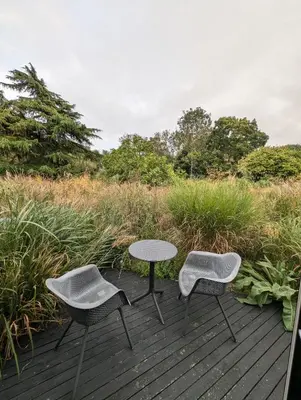 two chairs and a table on a wooden deck at Five Acre Barn in Aldringham