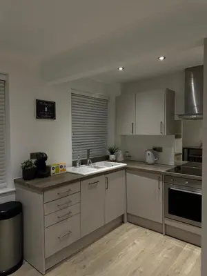 a kitchen with white cabinets and a sink at The Snug - Town Centre Apartment in Bishops Stortford