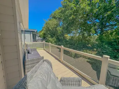 a porch with two chairs and a railing at Platinum lakeside Lodge on resort with fishing in Kelsale