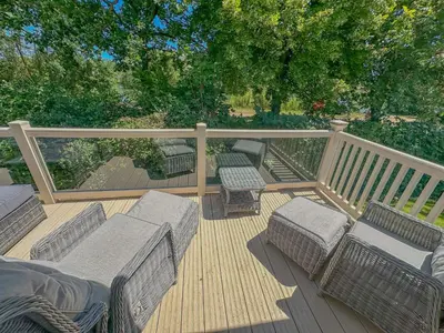 a deck with four chairs and a railing at Platinum lakeside Lodge on resort with fishing in Kelsale
