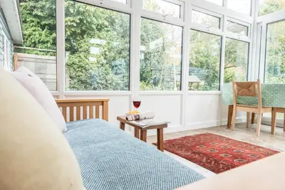 a bedroom with a bed and a table and windows at The Whins, Aldringham in Aldringham
