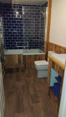 a bathroom with a toilet and a blue tile wall at St Edmunds Brewery in Downham Market