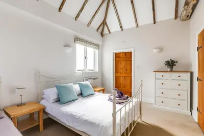 a bedroom with a white bed with blue pillows at Harestreet Farm Barns, The Dairy, Parlour and Creamery in Cottered