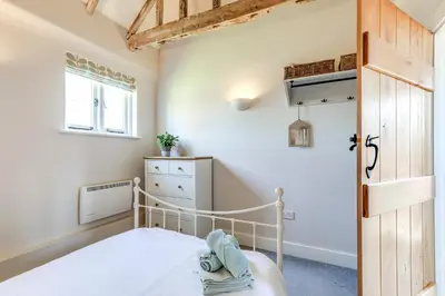 a bedroom with a bed and a wooden door at Harestreet Farm Barns, The Dairy, Parlour and Creamery in Cottered
