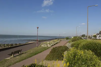 a path next to the ocean with a bench at Southend Guest House - Close to Beach, Train Station & Southend Airport in Southend-on-Sea