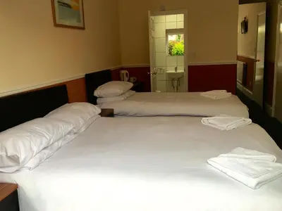 two beds in a hotel room with white sheets at Southend Guest House - Close to Beach, Train Station & Southend Airport in Southend-on-Sea
