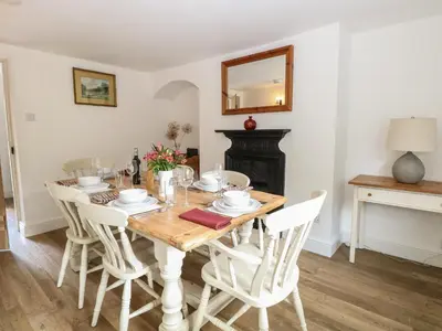 a dining room with a table with chairs and a mirror at Pear Tree Cottage in Swaffham