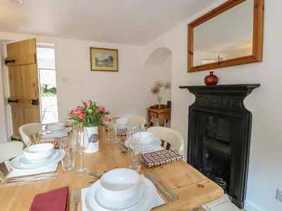 a dining room table with white dishes and a fireplace at Pear Tree Cottage in Swaffham