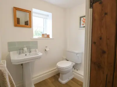 a bathroom with a toilet and a sink and a window at Pear Tree Cottage in Swaffham