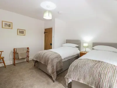 two beds in a room with white walls at Pear Tree Cottage in Swaffham