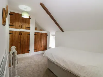 a bedroom with a bed and wooden cabinets at Pear Tree Cottage in Swaffham