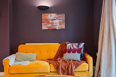 an orange couch with pillows on it in a room at Harland Haven Spacious 4br House In Ipswich in Ipswich