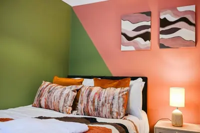 a bedroom with a bed with orange and green walls at Harland Haven Spacious 4br House In Ipswich in Ipswich