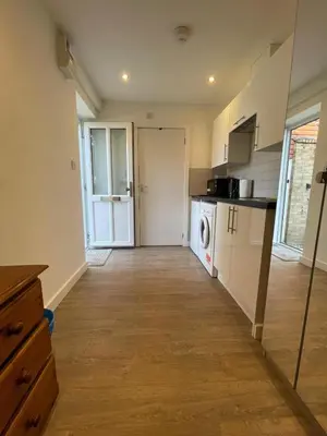 a kitchen with white cabinets and a wooden floor at 63 studio room for single or double occupancy in Brentwood
