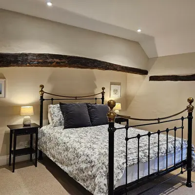 a bedroom with a bed with a black bed frame at The Old Flint Bank Cottage in Harleston