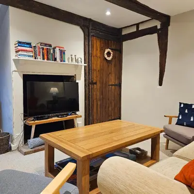 a living room with a table and a television at The Old Flint Bank Cottage in Harleston