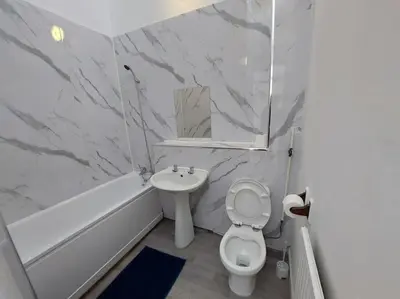 a bathroom with a toilet and a sink and a tub at 5 Bedroom House in Romford in Harold Wood