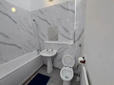 a white bathroom with a sink and a toilet at 5 Bedroom House in Romford in Harold Wood