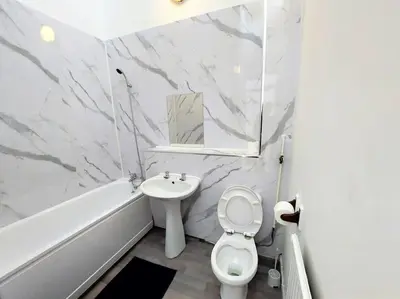 a white bathroom with a toilet and a sink at 5 Bedroom House in Romford in Harold Wood