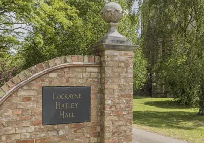 a brick wall with a statue on top of it at Cockayne Hatley Hall in Cockayne Hatley