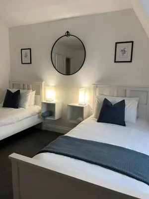 a bedroom with two beds and a mirror on the wall at The Nook - Town Centre Apartment in Hoddesdon