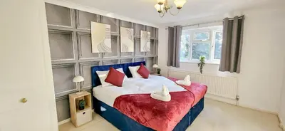 a bedroom with a large bed with red pillows at Chelmsford Comfort Retreat Spacious 4 Bedroom Sleeps 7 Free Parking in Widford