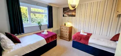a bedroom with two beds and a window at Chelmsford Comfort Retreat Spacious 4 Bedroom Sleeps 7 Free Parking in Widford