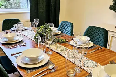 a long wooden table with plates and wine glasses at Chelmsford Comfort Retreat Spacious 4 Bedroom Sleeps 7 Free Parking in Widford